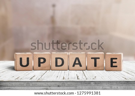 Update message sign on a wooden desk in a room with a blurry background Royalty-Free Stock Photo #1275991381