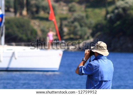 Man taking photos of a yachts in bay.