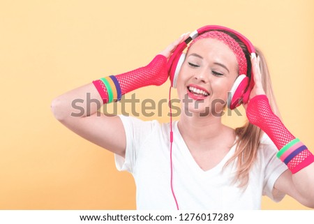 Woman in 1980's fashion with headphones on a pale yellow background