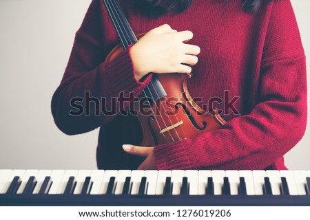 woman holding violin with piano