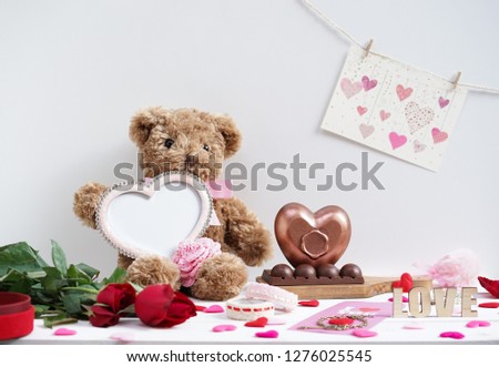 Happy Valentine's day. Teddy bear plush doll holding an empty beautiful pink heart frame for insert your personal message or photo. Heart chocolate on the side. Copy space on top for your text.