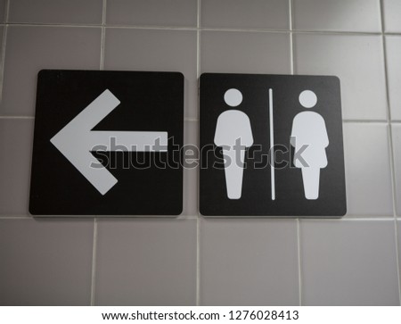 Signs pointing to public toilets for women and men.