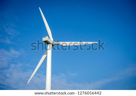 Wind turbine over the blue sky. A wind turbine, or alternatively referred to as a wind energy converter, is a device that converts the wind's kinetic energy into electrical energy.