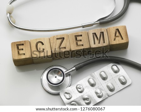 medical concept-Wooden block form the word ECZEMA with stethoscope and pils