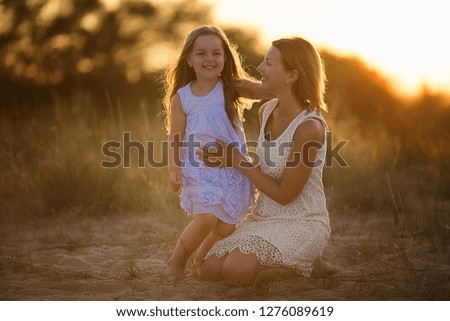 mother with daughter on the background of sunset in nature