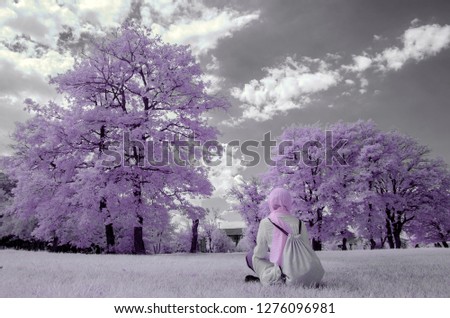 lady in a headscarf with perfect nature scene in the background pink trees infrared photo