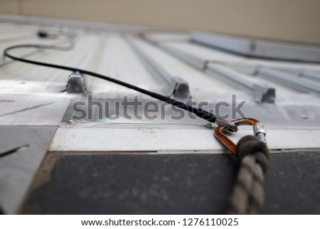 Picture of locking Karabiner connecting into first man safety line up permanently attached onto roof safety anchor point fall protection working at heights fall arrest