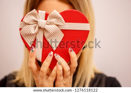 Gift box with a ribbon in female hands. The concept is suitable for love stories, birthdays and Valentine's Day
