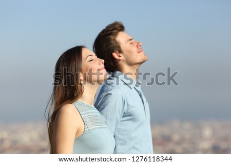 Side view of a relaxed couple breathing fresh air with an urban background