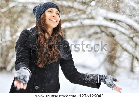 Beautiful girl playing with snow in winter park