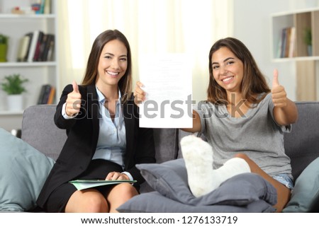 Happy insurance agent and disabled client showing contract with thumbs up at home