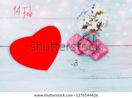 
pink gift wrap with red hearts and white flowers, on wooden background, glitter