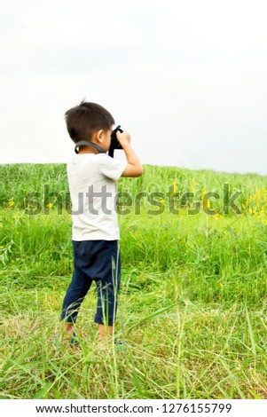 Asian Boy Taking Photo of Nature Country Side Yellow Flower Field with Digital Camera