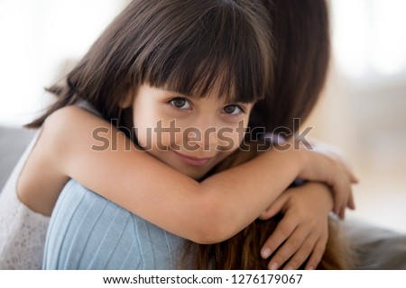 Adorable little daughter hugging mother looking at camera, mum and happy cute girl cuddling, smiling sincere child embracing mommy, childrens day, adoption, sweet kids love for mom concept, portrait Royalty-Free Stock Photo #1276179067