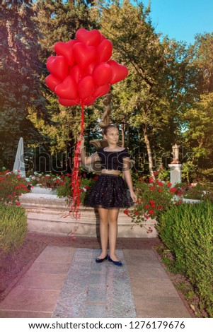 Pretty young girl with red balloons walking in the park - image. Air balloons. Holiday party, birthday and valentines. 