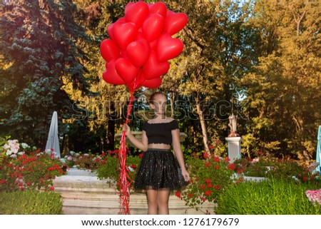 Pretty young girl with red balloons walking in the park - image. Air balloons. Holiday party, birthday and valentines. 