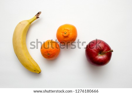 Flat lay picture of a banana, an apple and couple of satsumas.