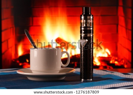electronic cigarette and cup of coffee on fireplace background