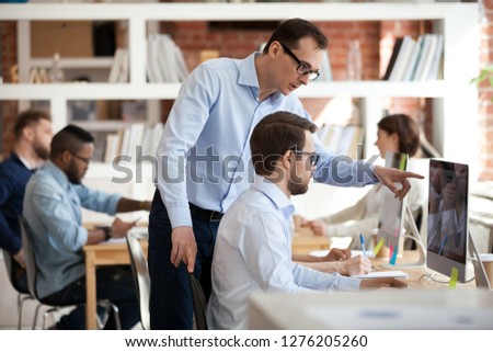 Executive corporate manager ceo helping male colleague with computer task in office, mentor talking supervising teaching training intern coworker explaining online work pointing on pc at workplace Royalty-Free Stock Photo #1276205260