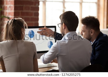 Rear view at business corporate analysts employees talking discussing work results at team meeting, colleagues analyzing data online marketing report company sales growth statistics in office Royalty-Free Stock Photo #1276205275