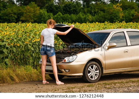 The girl looks at the engine of the car. The driver is the girl near the broken car.