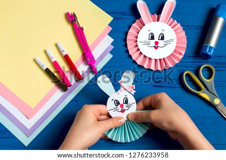 Child makes bunnies out of paper for Easter decoration. Creative idea for children's party. DIY concept. Step by step photo instruction. Step 15. Glue bunny head 
