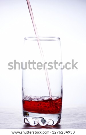 pouring a red drink into a glass, on a light background, isolate