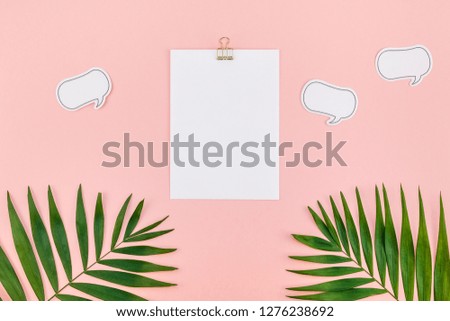 Creative flat lay top view mock up blank paper sheet postcard clip board green tropical palm leaves on millennial pink paper background copy space. Minimal tropical palm leaf plants summer concept