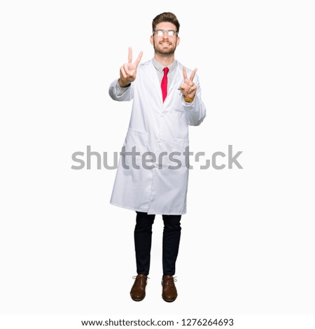 Young handsome scientist man wearing glasses smiling looking to the camera showing fingers doing victory sign. Number two.