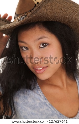 A close up of an Asian woman in her cowgirl hat with a small smile on her lips