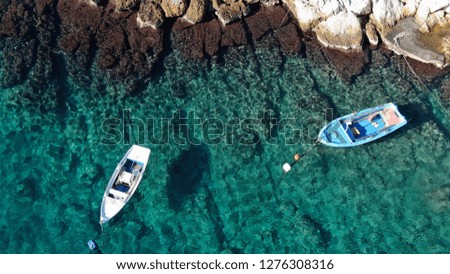 Aerial drone bird's eye top view of traditional fishing boat in port of Mykonos in sapphire clear waters, Cyclades, Greece