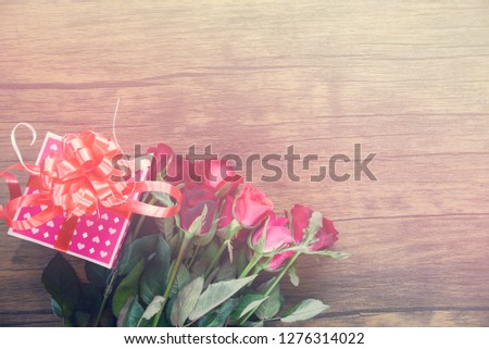Pink gift box and red roses flower love on wooden table rustic background tone vintage top view