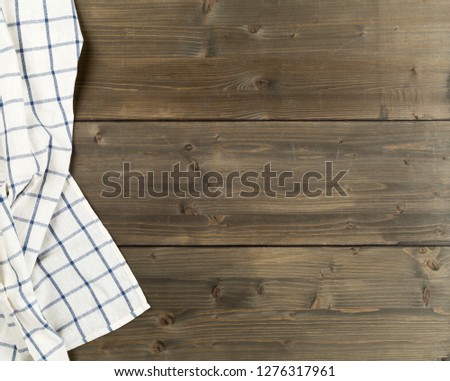 Blue and white checkered dishcloth on brown rustic wooden plank table flat lay top view from above with copy space