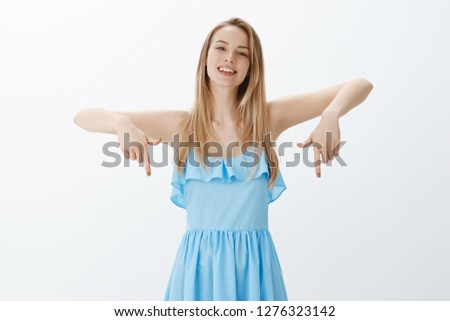 Hey check out my outfit, look down. Portrait of charming good-looking and friendly bright blonde female student on prom hanging out with friend in blue dress pointing downwards as showing cool shoes