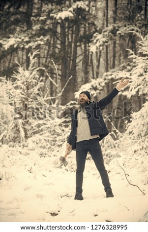 skincare and beard care in winter, beard warm in winter. Man lumberjack with ax. Temperature, freezing, cold snap, snowfall. Camping, traveling and winter rest. Bearded man with axe in snowy forest.