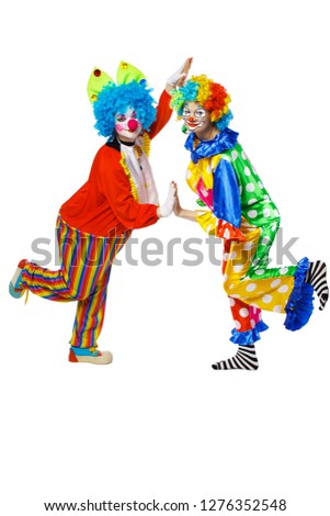 Two clowns stand sideways on one leg and lean on each other with the palms of their hands. Isolated background