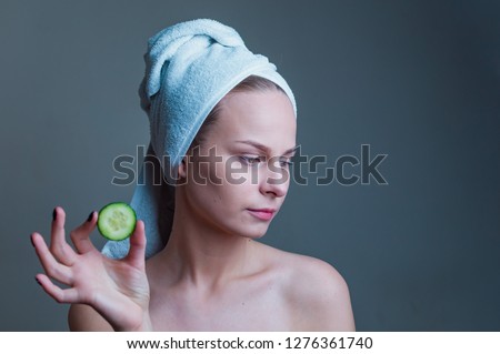 Young beautiful girl with perfect clean skin smiling holding cucumber slices over white background. Beauty cosmetology and spa