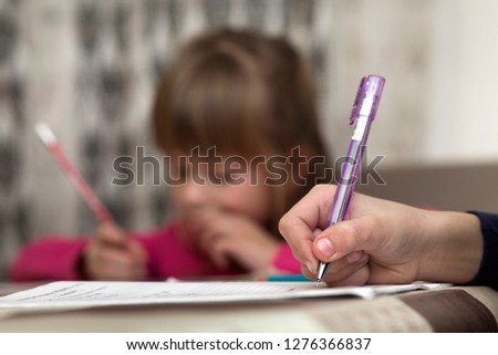 Portrait of cute pretty little serious child girl drawing with pencil on paper on blurred background. Art education, creativity, doing homework and children activities concept.