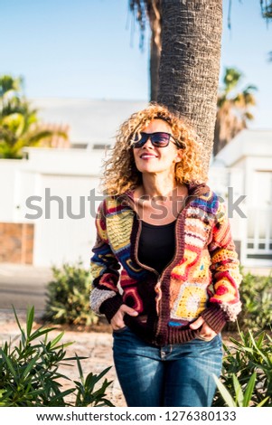 Vertical portrait beautiful curly middle age woman enjoying the sun and the leisure outdoor day activity smiling and resting - trendy fashion clothes and sweater for model casual concept image happy