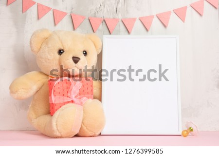 Children's toys, a teddy bear and a frame on a light wall background, for design, layout. Baby shower