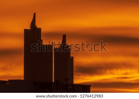 Silhouette photo of skyline building on colorful twilight sunset sky background . Skyscraper on orange sky in big city. Dust and air pollution made light scattering.
