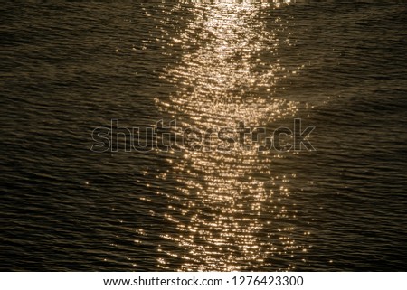 Beautiful sunset reflection sparkles on tiny ripples of sea water wave , close up