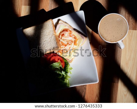 Top view picture of Ham Cheese Sandwich and a cup of cappuccino with window light effect.