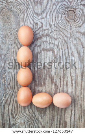 A letter l from the eggs for Easter. On a wooden texture.