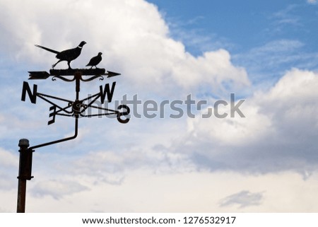 Wind vane isolated on a cloudy sky background. Wind direction concept image. 