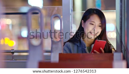 Woman use of mobile phone on tram in Hong Kong at night
