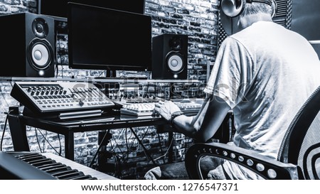 back of male DJ, producer, composer, sound engineer, editor working in sound studio, broadcasting studio, home studio for post production
