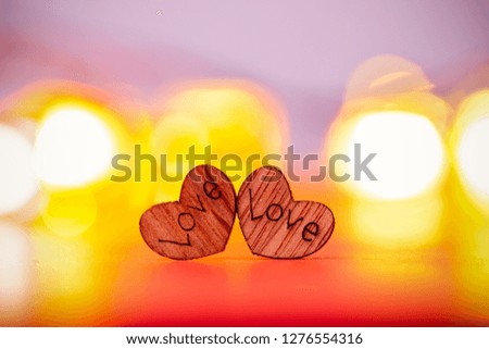 Two wood hearts on red background with blured lights.