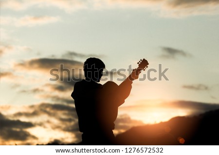 Young christian worship God and playing guitars with light sunset background,christian concept.