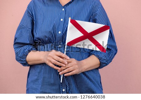 Alabama state flag. Close up of hands holding Alabama flag.